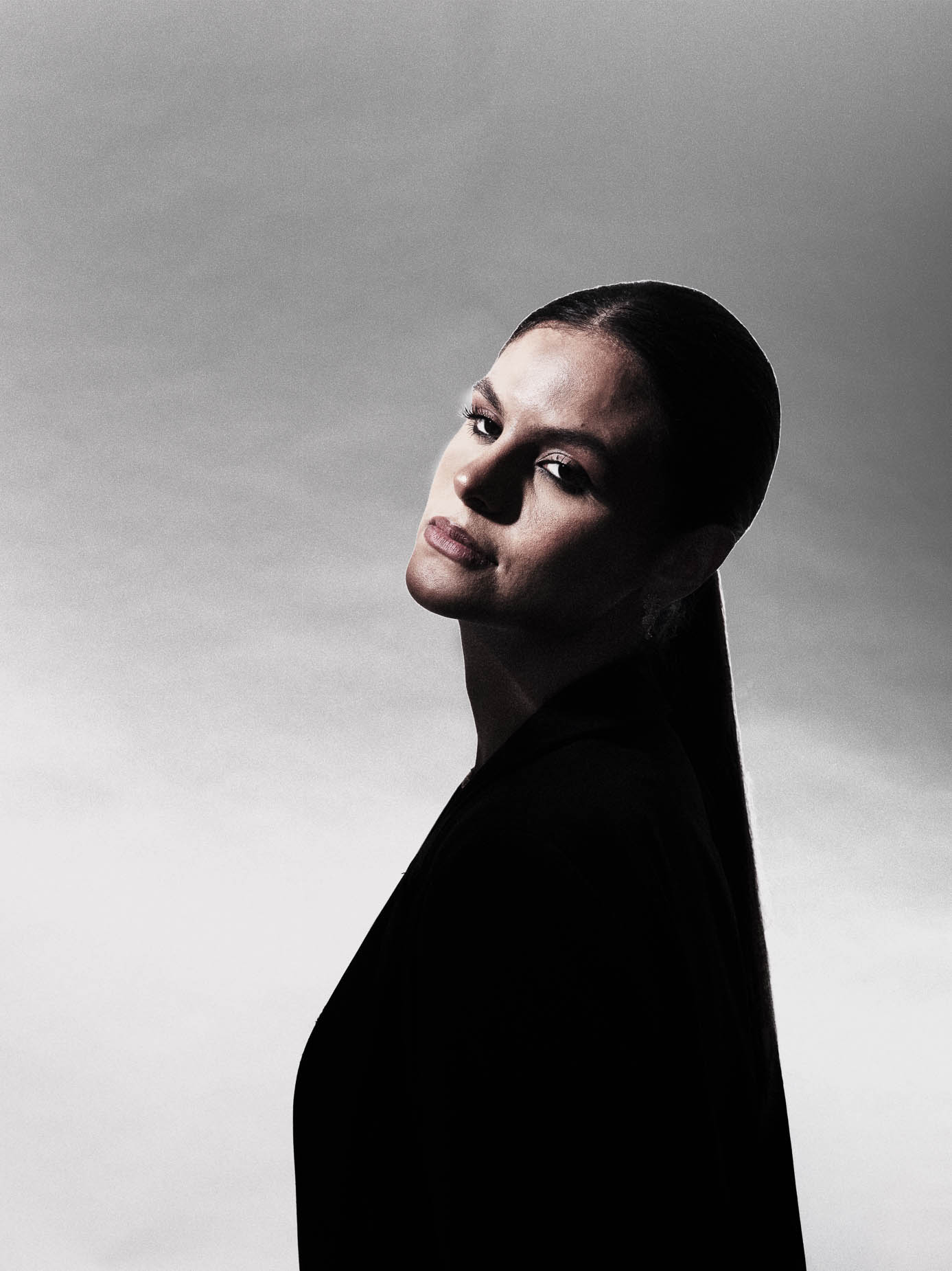 Low-key beauty studio portrait, dramatic gesture with one hand raised beside the face