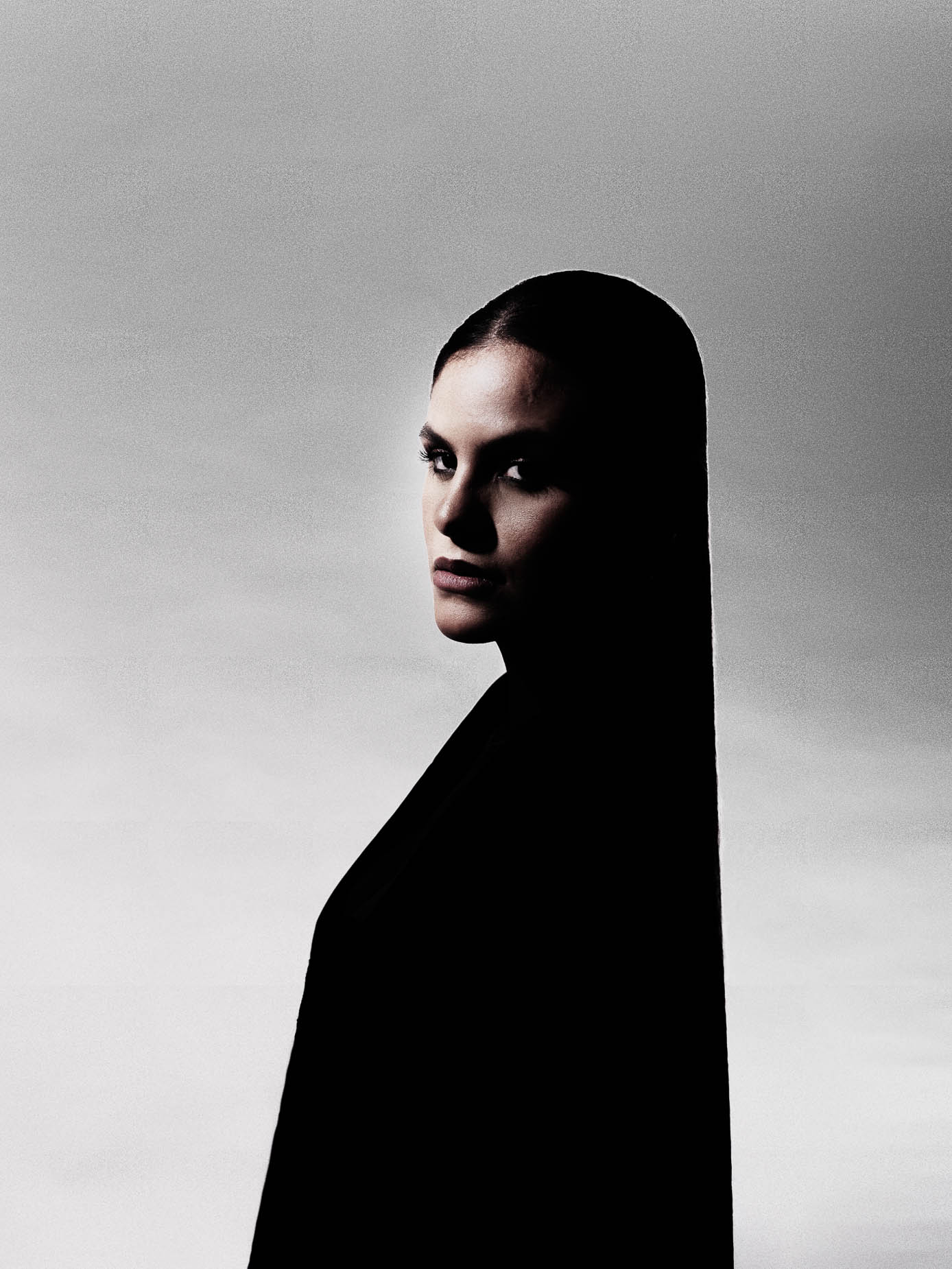 Low-key beauty studio portrait, face lit from one side against a dark background