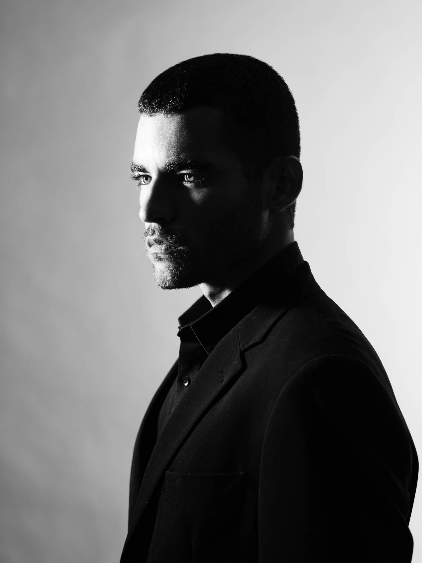 Man facing the camera in a dark turtleneck, low even lighting across the face, calm and direct gaze