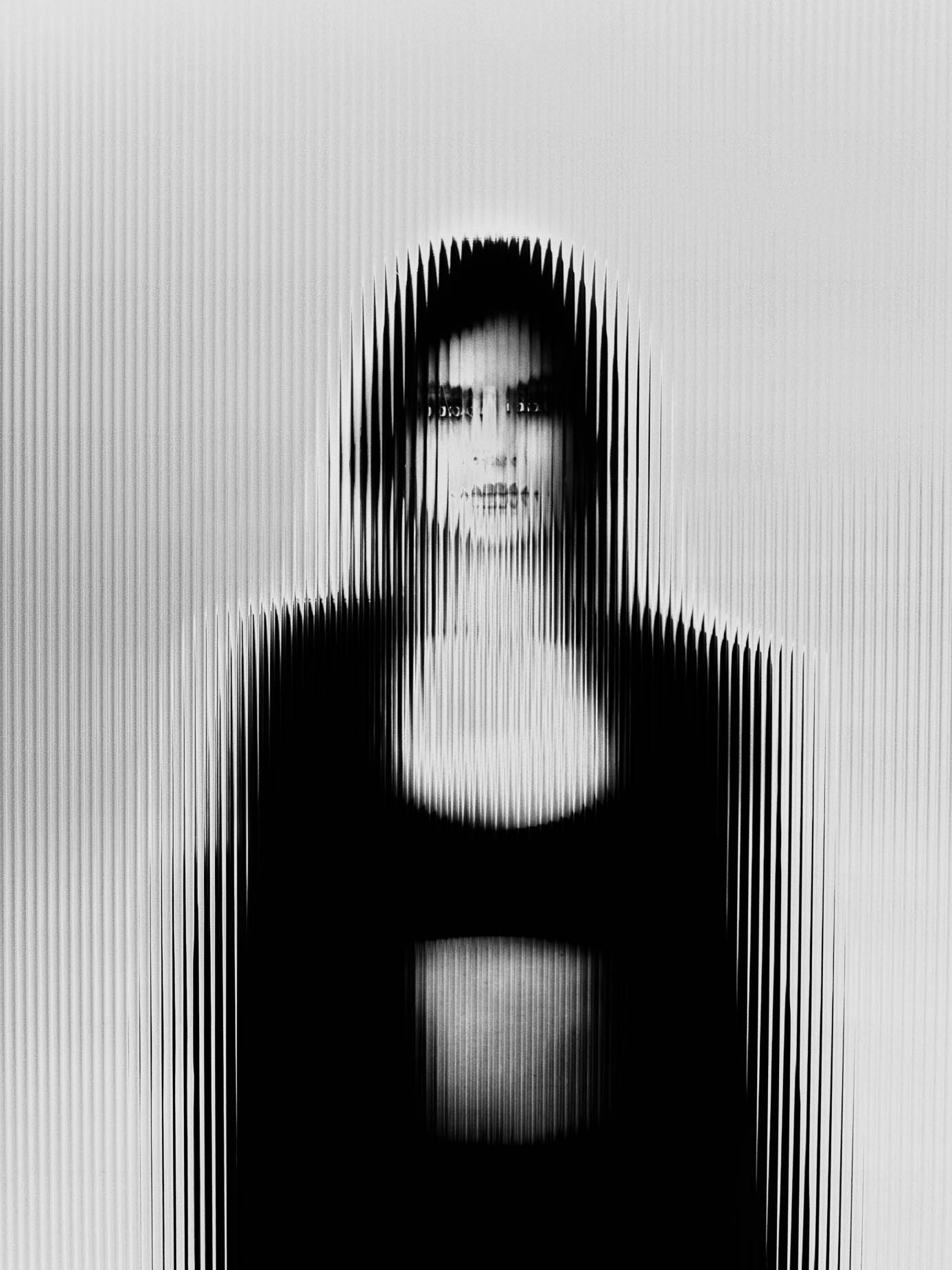 Portrait glimpsed through fluted glass, contour loosening into vertical striped bands against a plain background