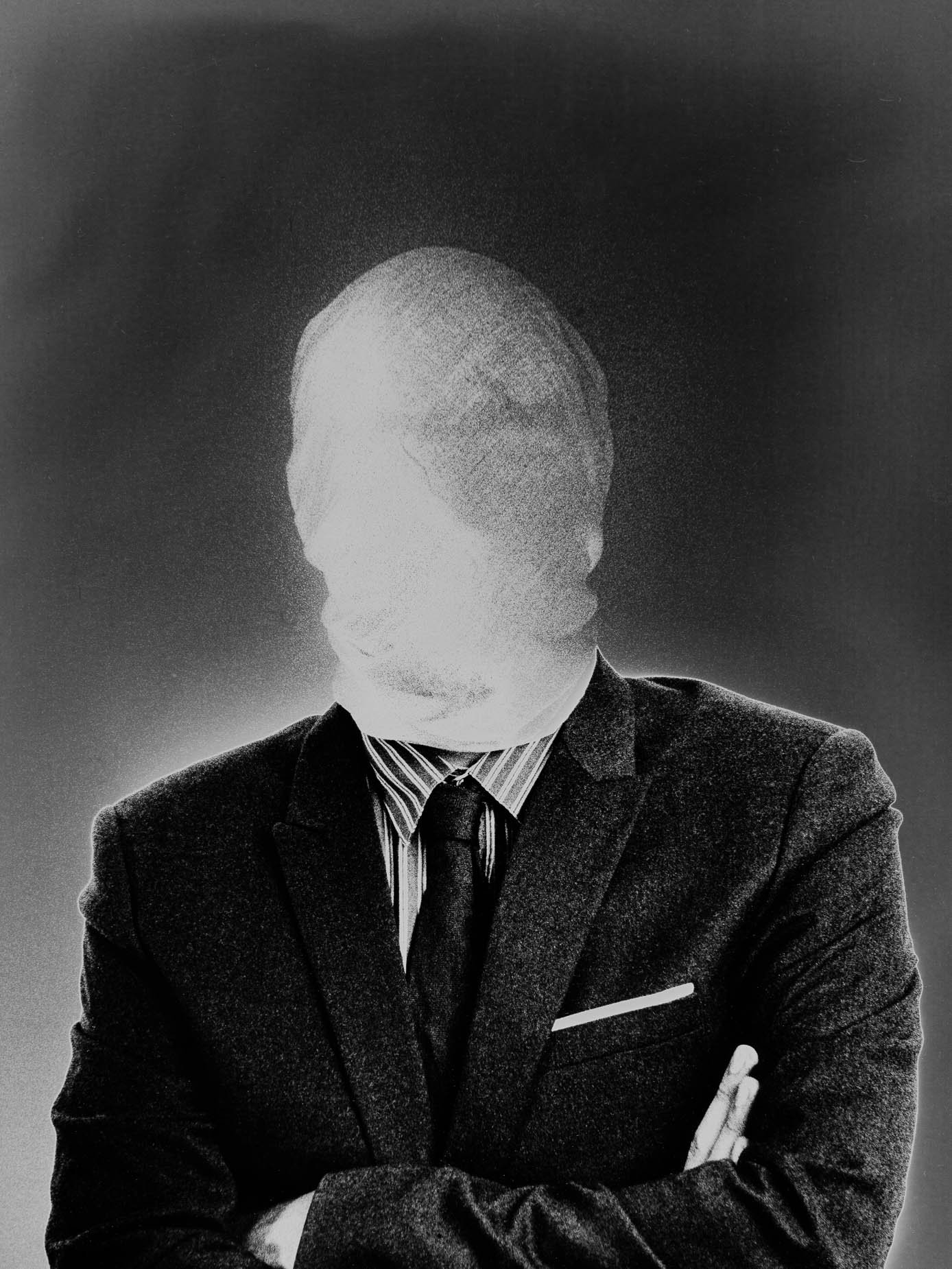 A man in a light suit with arms crossed, his face reduced to a pale motion-blurred blank, tie and jacket in sharp focus