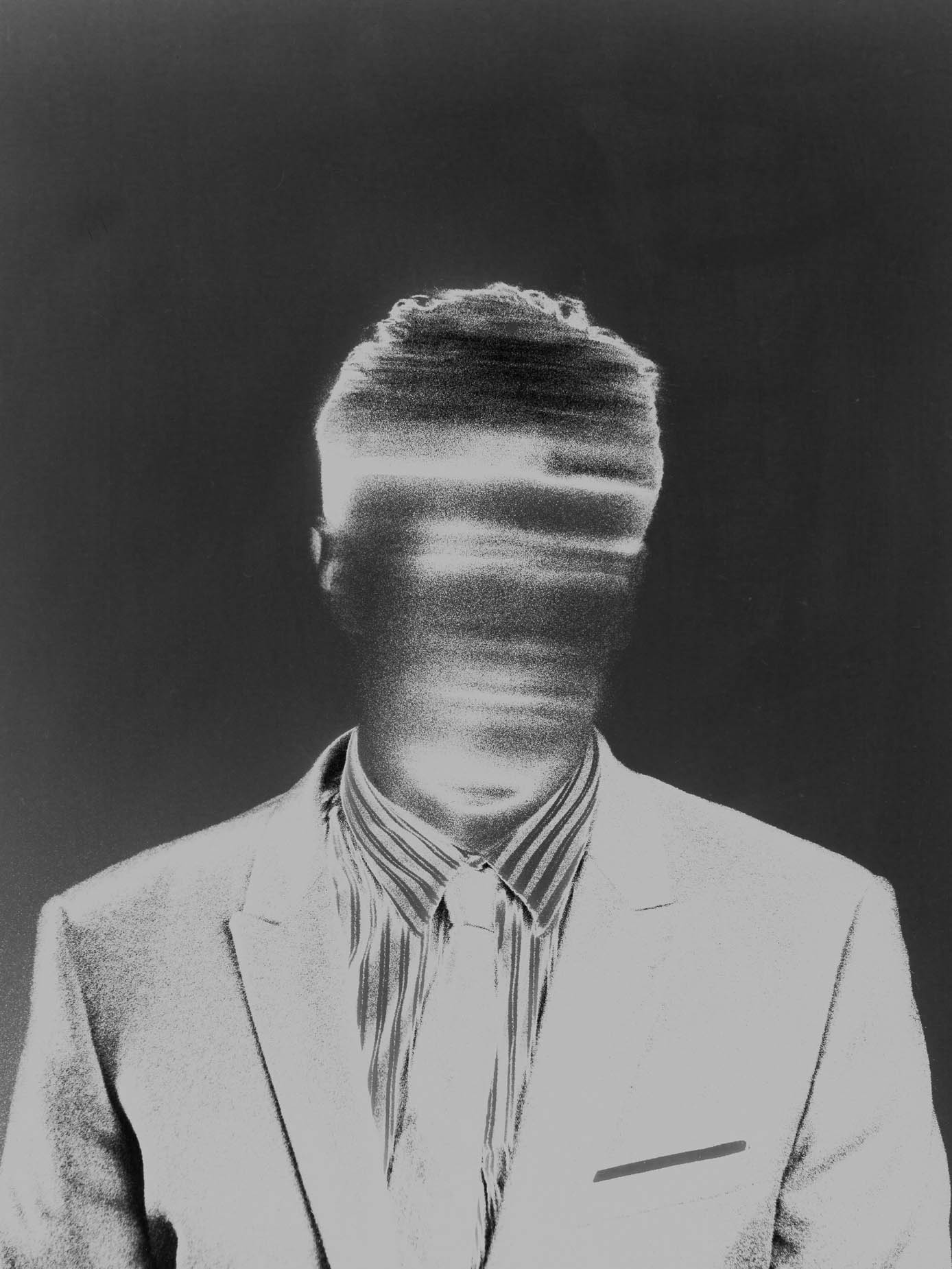A man in a striped shirt, tie and suit jacket, his face rendered as a vertical motion blur so no features are visible, hair in sharp focus above