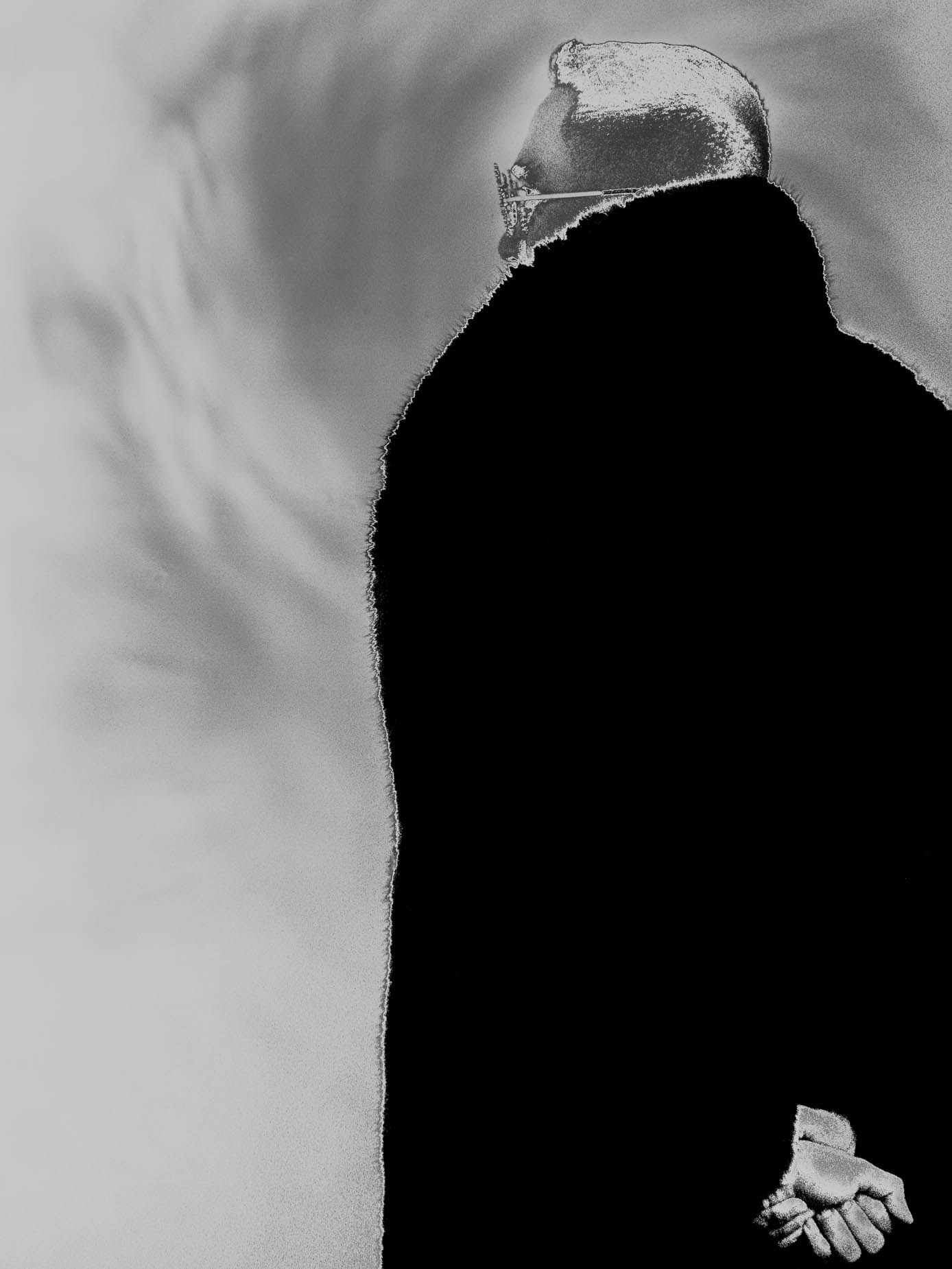 A hand reaches toward a solid black circle, fingers curled as if brushing its edge, set against a plain pale background